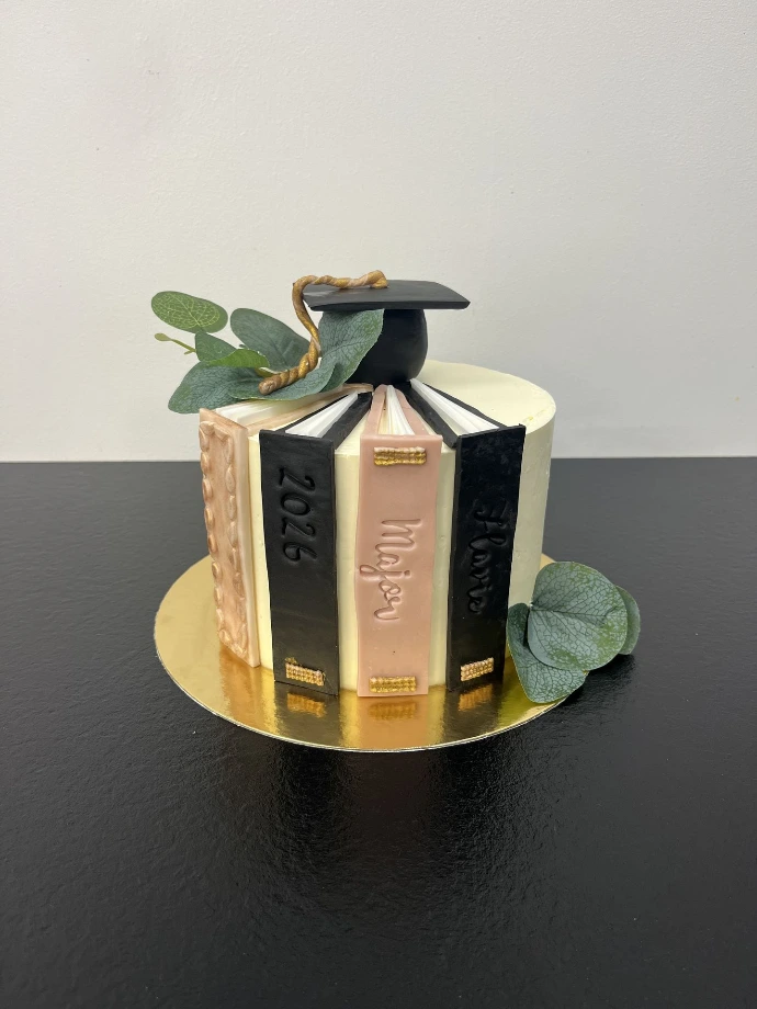 Gâteau personnalisé blanc, rose et noir, sur le thème des livres.