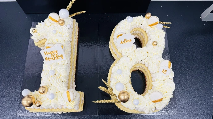 Gâteau chiffre 18 blanc et doré avec décoration élégante.