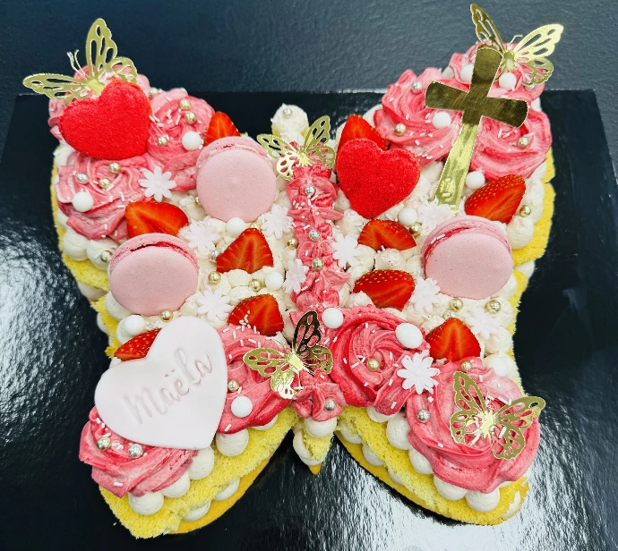 Gâteau en forme de papillon décoré de fraises et de douceurs roses.